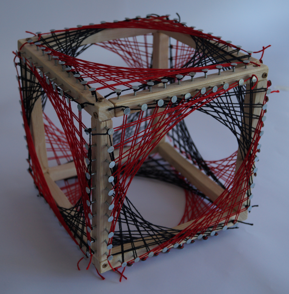 A cube made from wood, with hollow sides. Along the edges of the cube, nails are added. These are connected across the faces of the cube by strings.